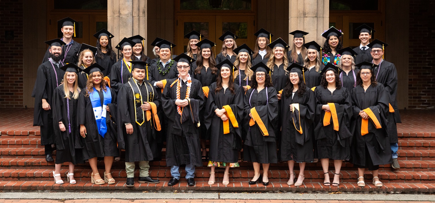 Web Banner - MSN Grad Group A group of 20+ MSN grads pose for a group photo, wearing robes and grad caps. Draped over one arm are their black and golden hoods for their hooding ceremony.