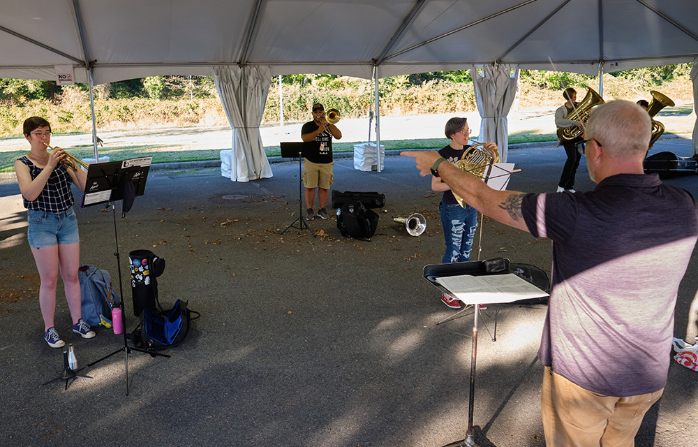 Brass and wind students rehearse outdoors with Dr. Edwin Powell conducting.