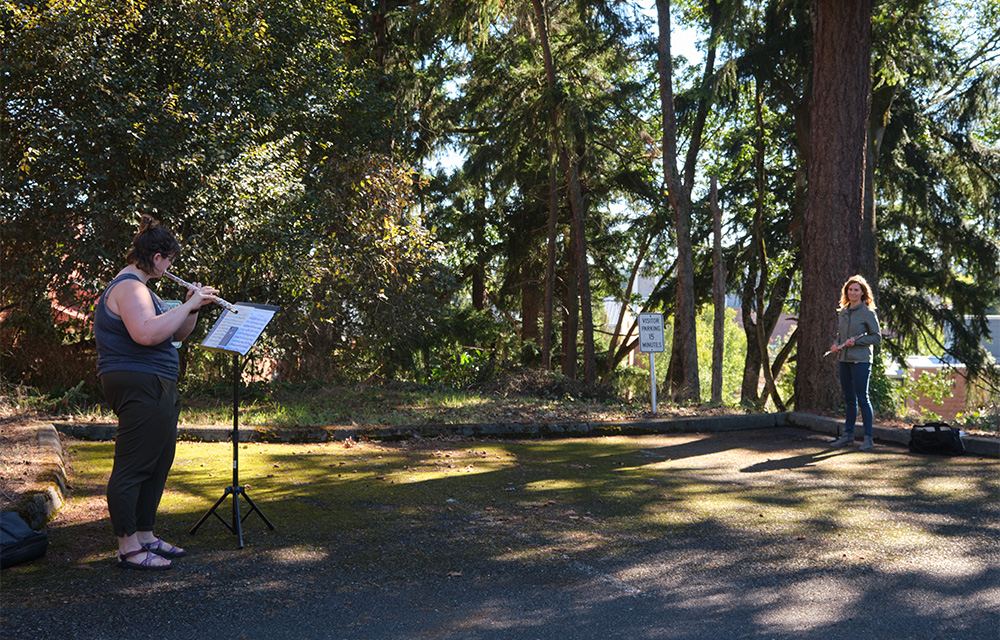 Dr. Jennifer Rhyne conducts a socially distant outdoor flute lesson with student Paige Balut in the parking lot next to the Mary Baker Russell Music Center.