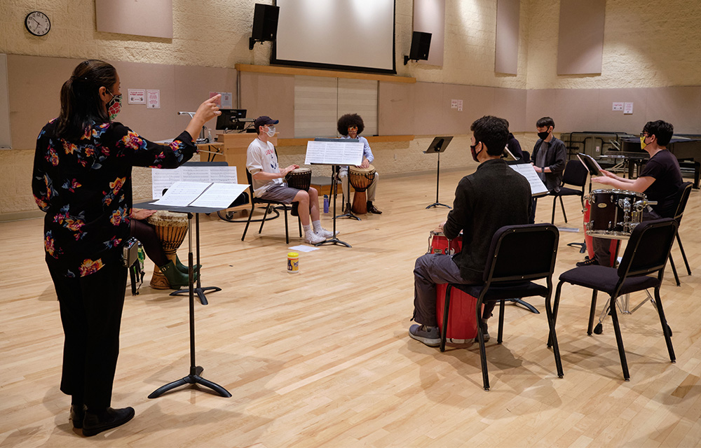 Dr. Miho Takekawa conducts a socially distant Percussion Ensemble class in a large rehearsal space in the music building.