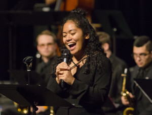 Student singing into microphone on stage