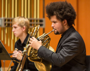 Wind ensemble member playing french horn.