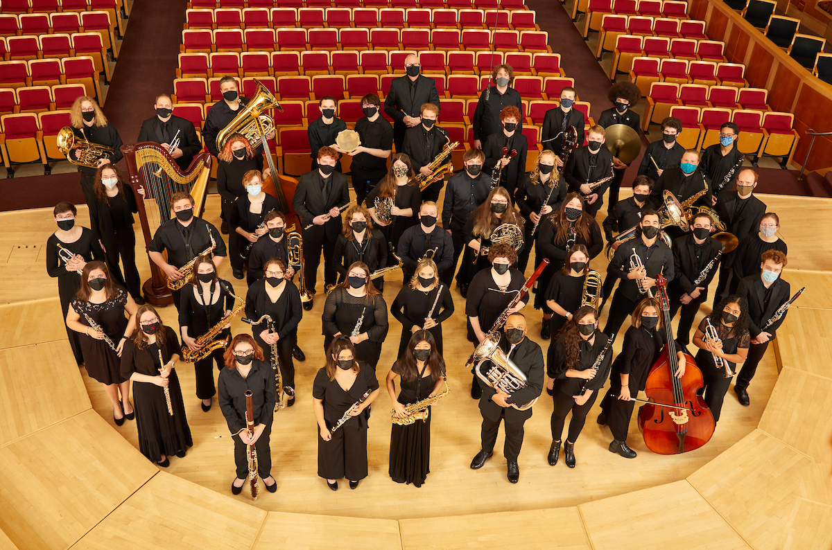 PLU 2022 Wind Ensemble in Lagerquist Concert Hall. Students are dressed in black, wearing masks, and holding their instruments.