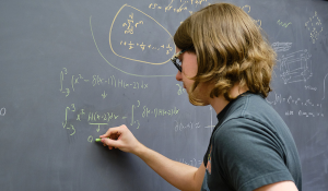 student writing on chalkboard