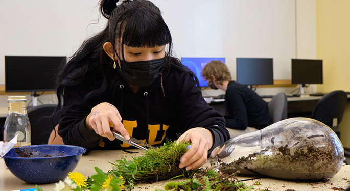 a student works with moss at a table