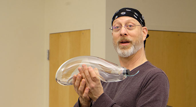 Professor Heath holding an empty glass biosphere