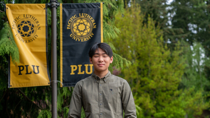 Brandon Nguyen in front of PLU flags.