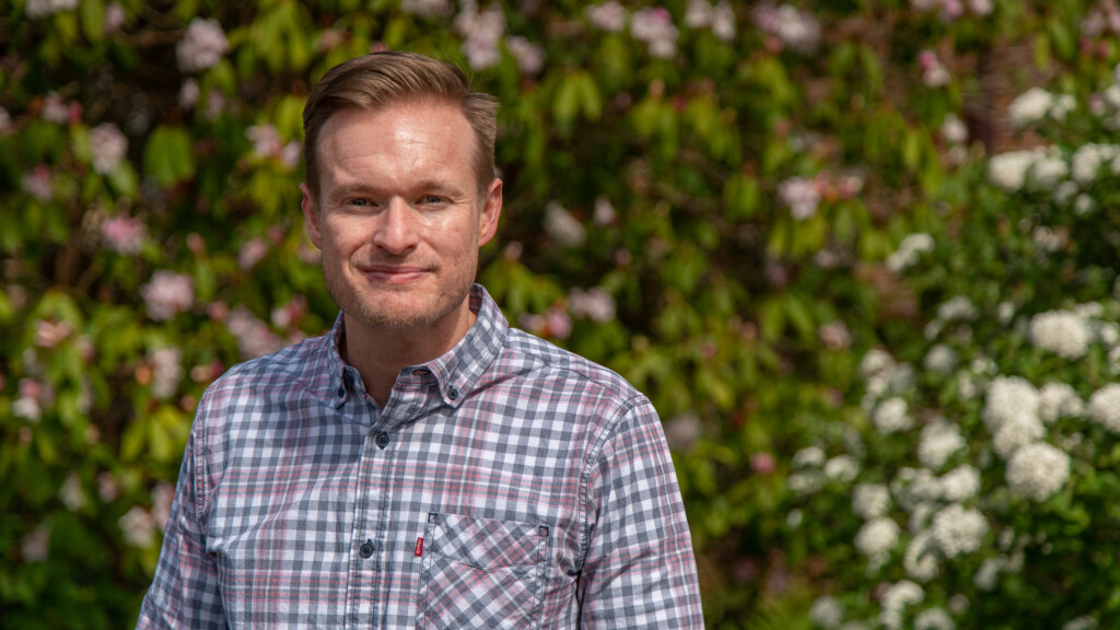 Corey Cook in front of flowering bushes