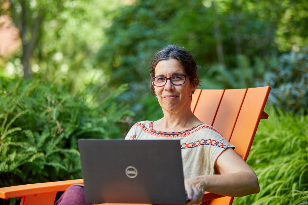 Ksenija Simic-Muller in an orange chair with a laptop.