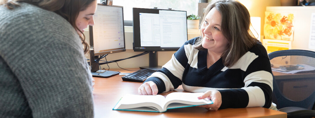 Professor Tiffany Artime sitting at her desk talking to a student.