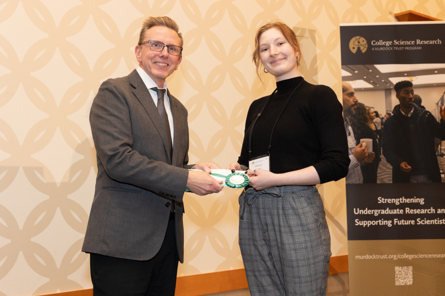 Psychology student Victoria shaking hands and accepting a prize from an official.