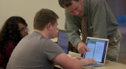 Professor teaching students on a laptop