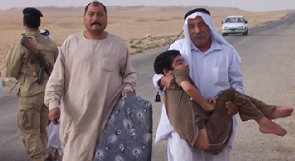 In the distance as the dust sifts through the air, a middle-aged Iraqi man walks to a makeshift United States military medical station. Draped in his arms is a young child, his son. It is apparent the boy does not have the use of his legs. His father has brought his son to get a wheelchair.