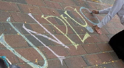 Student writing UnPLUgged on the brick