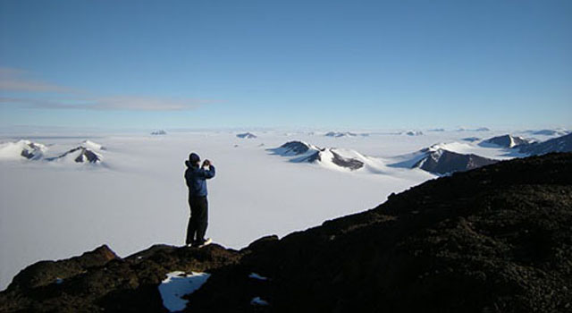 Person standing on rocks overlooking foggy Anatartica valley