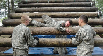 ROTC students climbing over logs