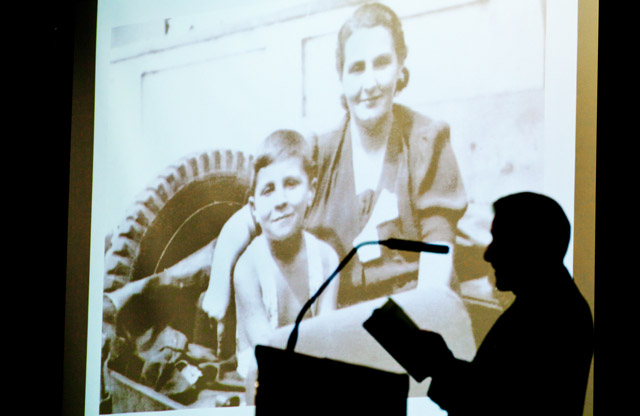 George Elbaum reads from his book “Neither Yesterdays Nor Tomorrows” about his survival in Poland during WWII. On the screen behind him is a picture of Elbaum and his mother taken shortly after the war ended. (Photo by John Froschauer)