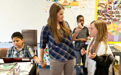 Fourth grade teacher Jessica Edwards '11 talks with one student while lending a comforting hand to another.