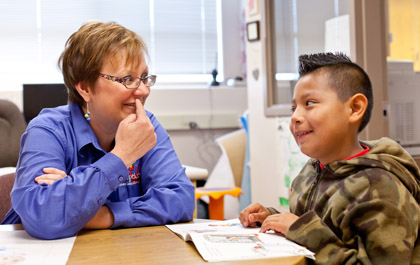 Principal Kristen Schroeder '90, '97 works one-on-one with a student on reading in her office.