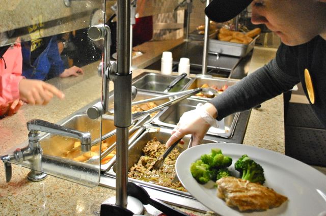 A student worker serves dinner in the University Commons.