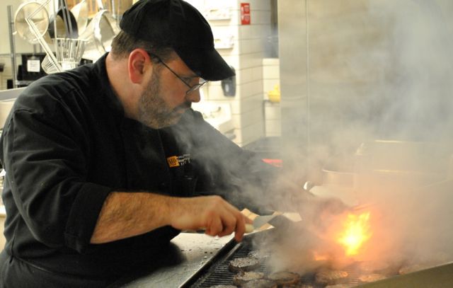 Erick Swenson grills small burgers for a weekend event on campus.