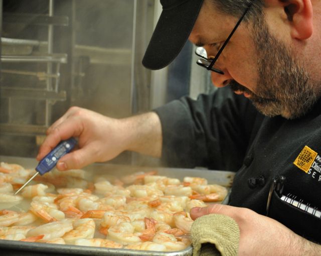 PLU chef Erick Swenson ’91 checks on a tray of shrimp from the oven.