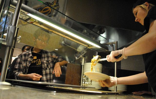 A student worker serves up a bowl of pasta during dinner in the University Commons.