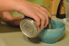 person pouring contents of a can into a bowl