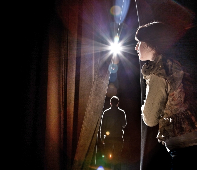 Chris Albert on stage at the new Karen Hille Phillips Center for the Performing Arts with a student peaking past the curtain