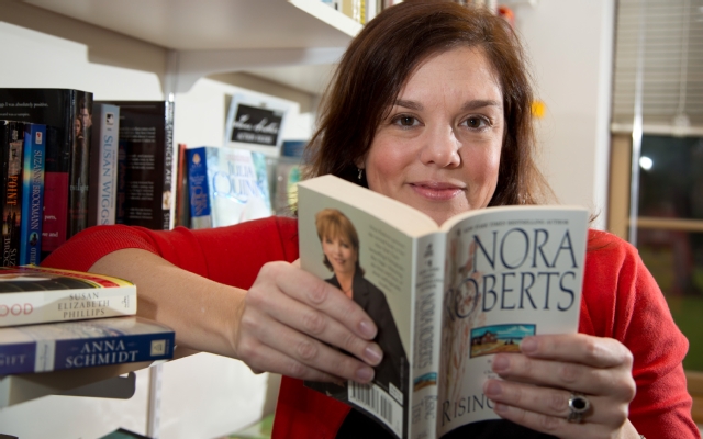 Professor of Sociology Joanna Gregson reads a novel by Nora Roberts, one of the highest-selling romance authors of all time. Gregson interviewed Roberts as part of her research on the writers of romance novels.