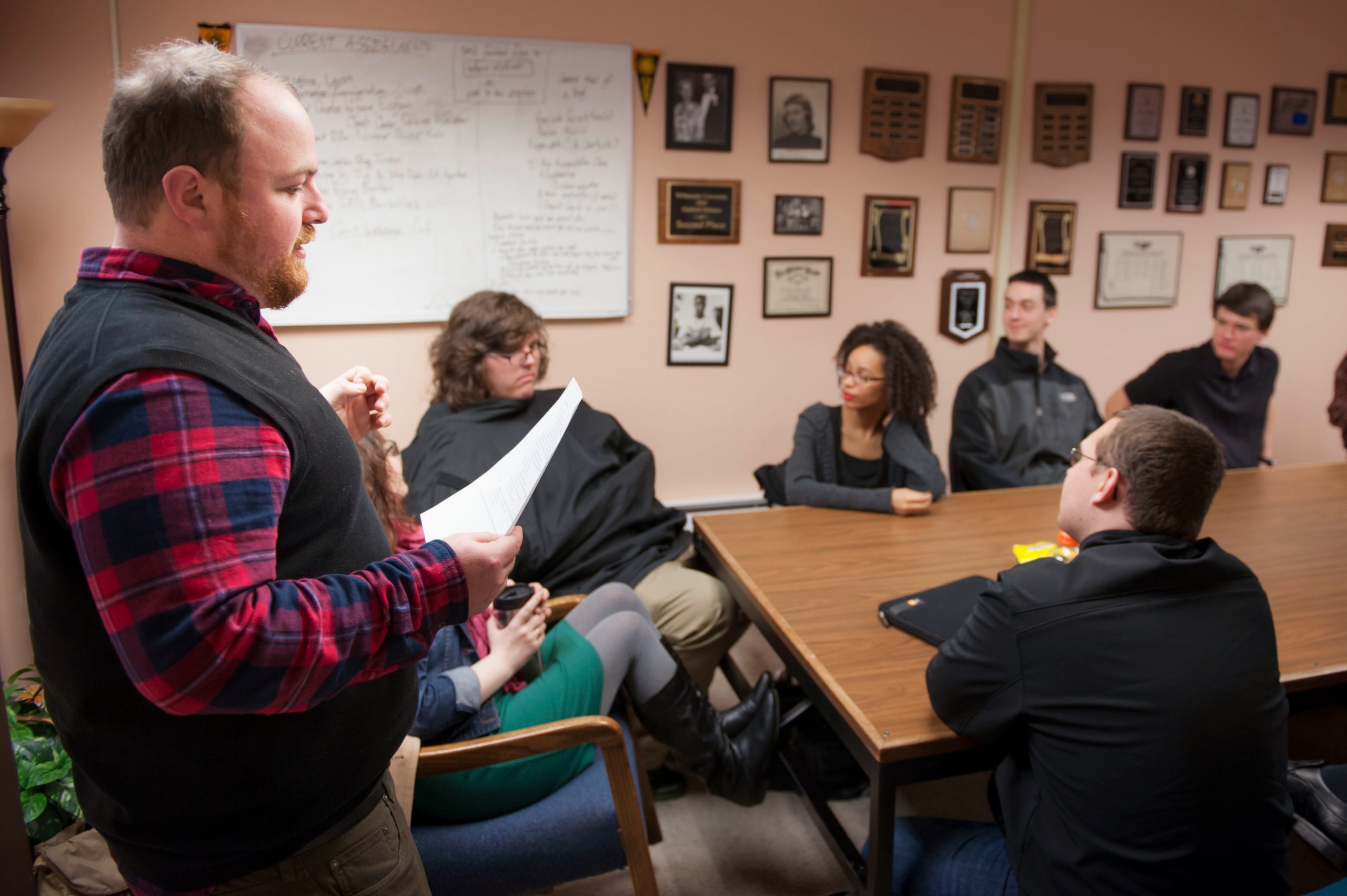 Coach Justin Eckstein, left, addresses the Speech and Debate team, including Pam Barker ’14 (behind Eckstein) and David Mooney ’14 (corner of table). (Photo: John Struzenberg / PLU student)