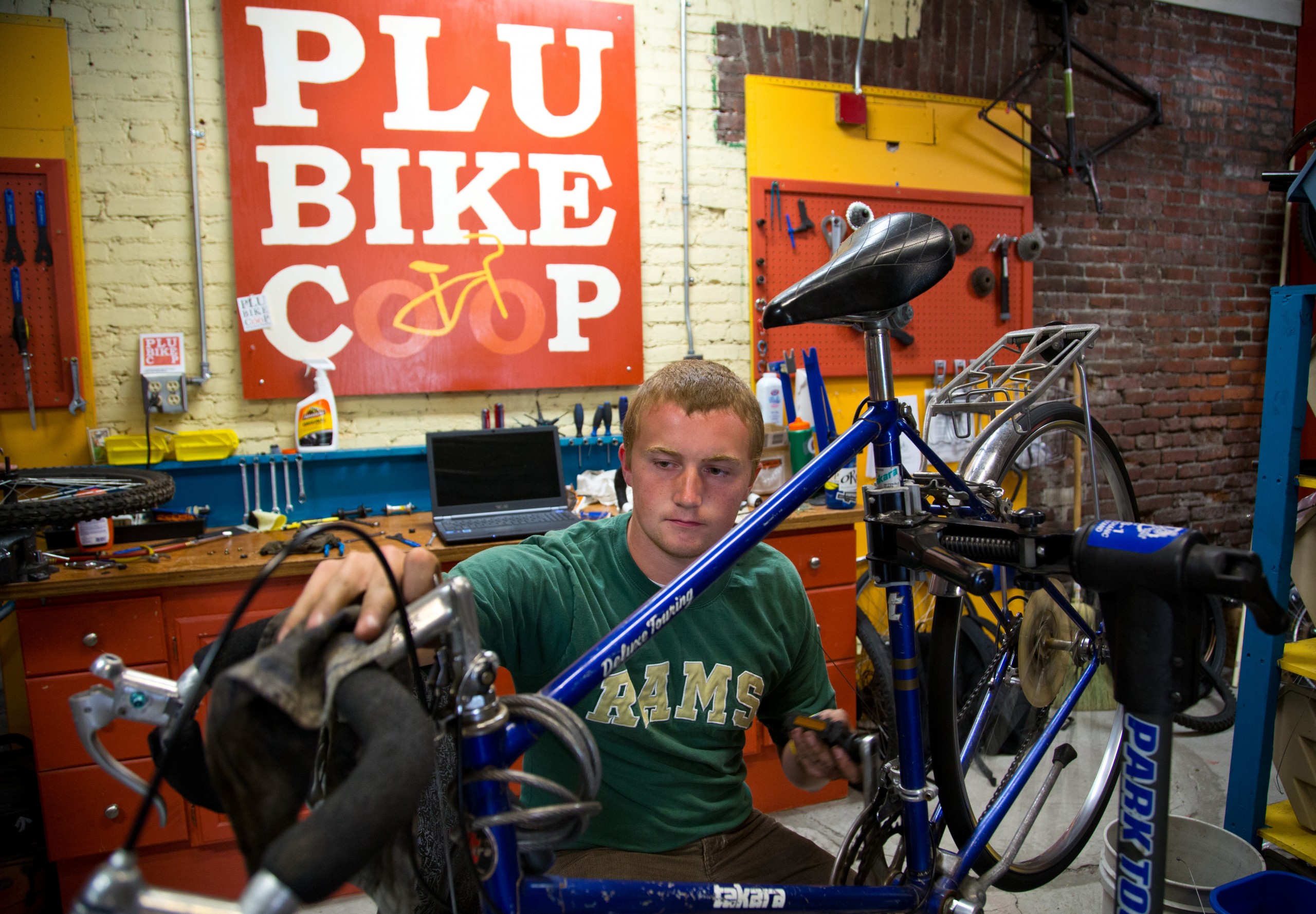 Isaac Moening-Swanson ’15 works inside PLU’s Bike Co-op. (Photo: John Froschauer / PLU)