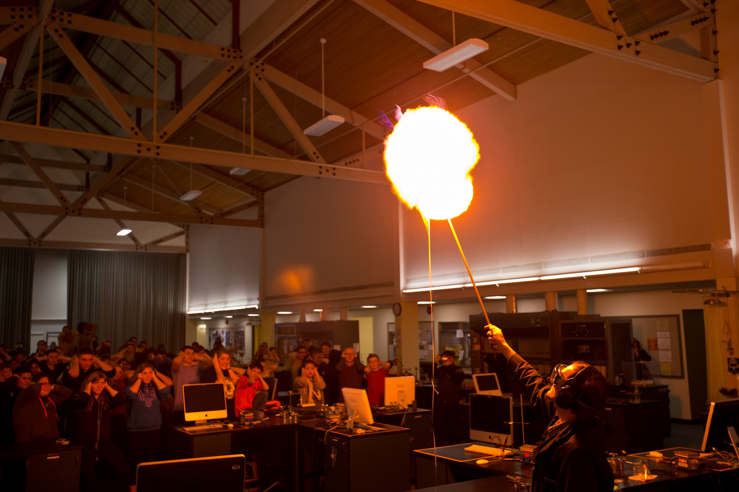 Students cover their ears as a balloon filled with hydrogen and oxygen bursts during the Chemistry Department’s Desserts and Demos Night on April 15. (Photo: John Froschauer/PLU)