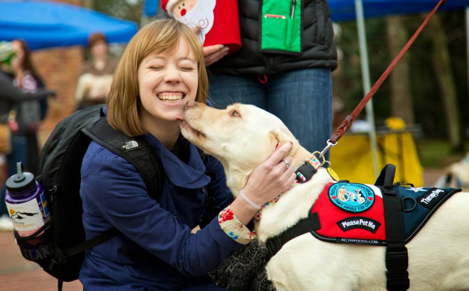 PLU student Maylen Anthony ’16 gets a kiss from Addy the therapy dog during finals week in December 2013. ASPLU will bring more pets to campus for Spring finals week, May 19-23. (Photo: John Froschauer/PLU)