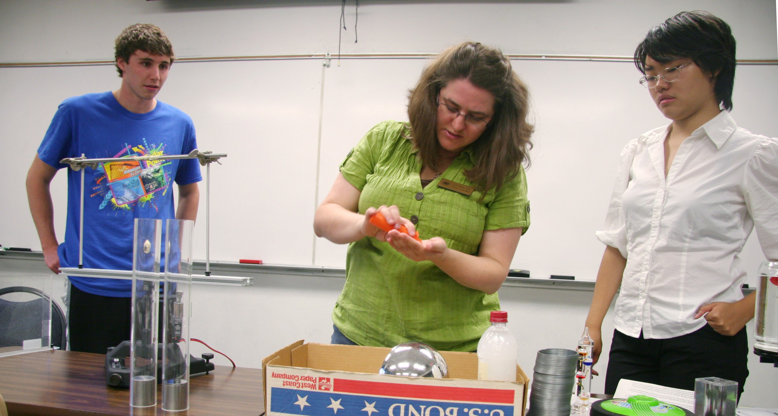 Katrina Hay, Associate Professor of Physics, center, works with Brian Ruggles, left, and PLU Physics Club Michelle Zhai on a demonstration for the Sept. 26 Physics Demo Theater. (Photo: Shunying Wang ’14)