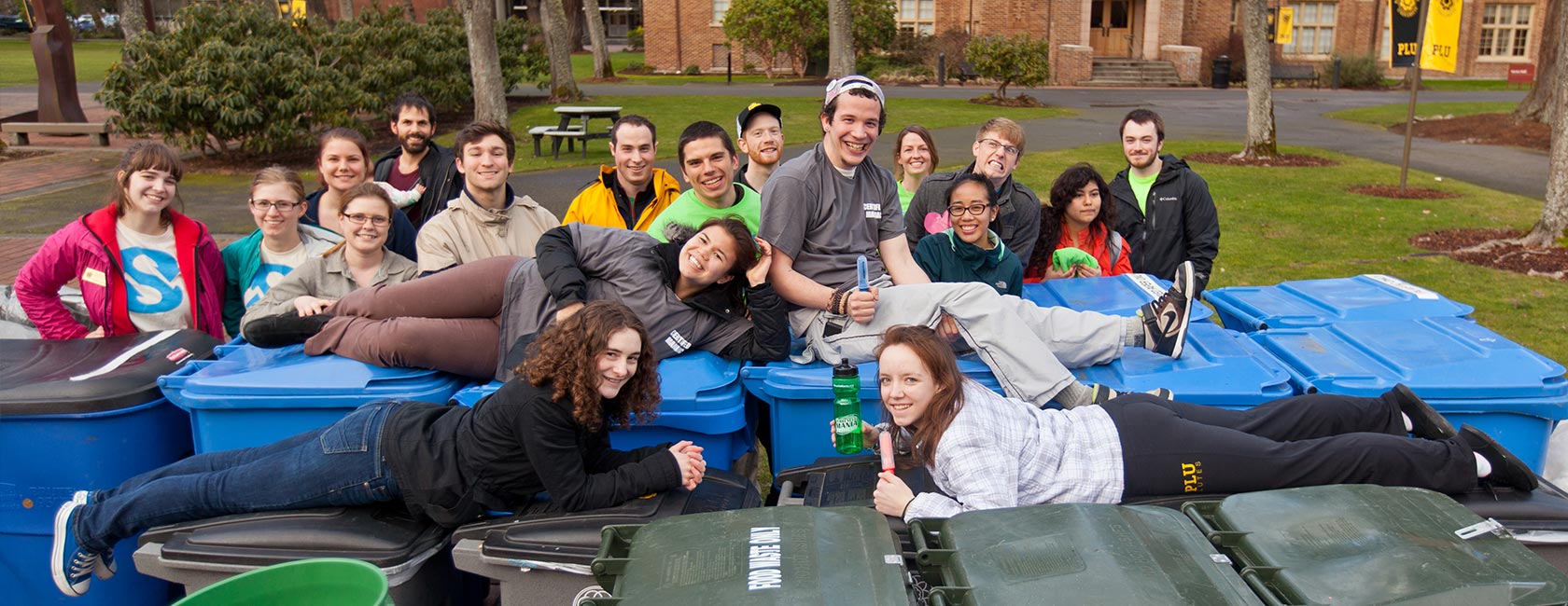 4 students posing on top of the recycling containers