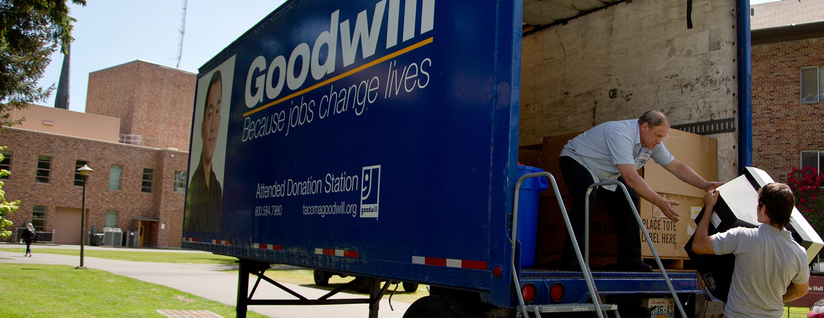 Goodwill trailer with a student giving an employee a TV