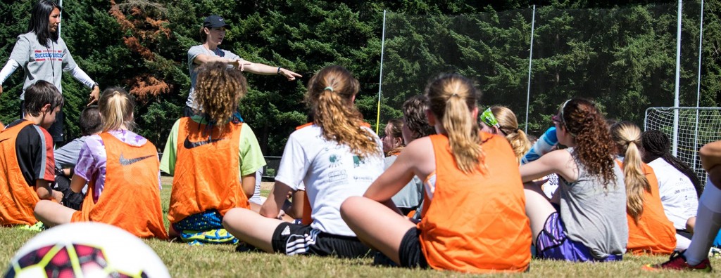 Colleen Hacker's Success Soccer Camp, young people sitting in the grass listening to coaches.