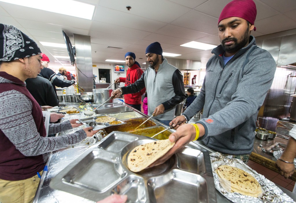 PLU students participate in langar, the free, vegetarian community meal served from the kitchen in the gurdwara. Miguel Castillo (left) waits to be served. Sikh-Americans participate in seva, or service to the community by donating ingredients, cooking and serving free vegetarian food.