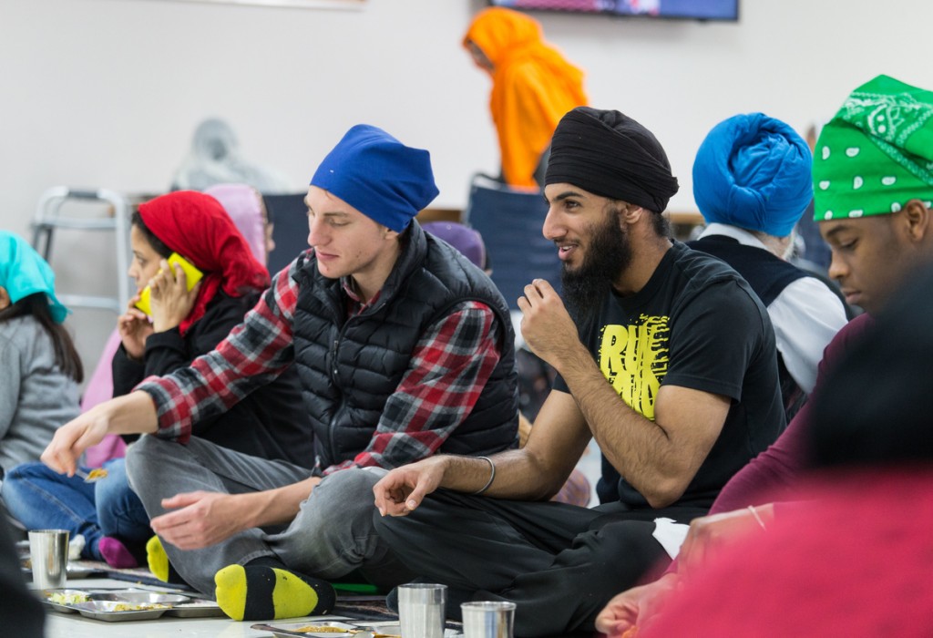 Joel Frykholm (left) and Deshawn Williams (right) share langar with Jaspreet (middle), a member of the Renton Sikh community.