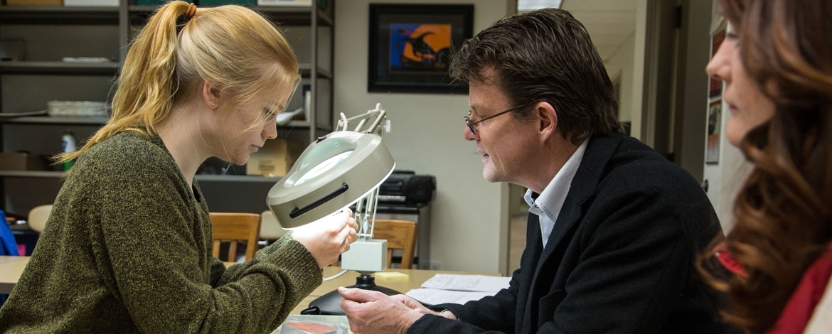 Professor Bradford Andrews with Emma Holm '17 (left) and Georgia Abrams '17 (far right) look over artifacts collected at Mount Rainier in PLU's anthropology lab on Wednesday, March 9, 2016. (Photo: John Froschauer/PLU)