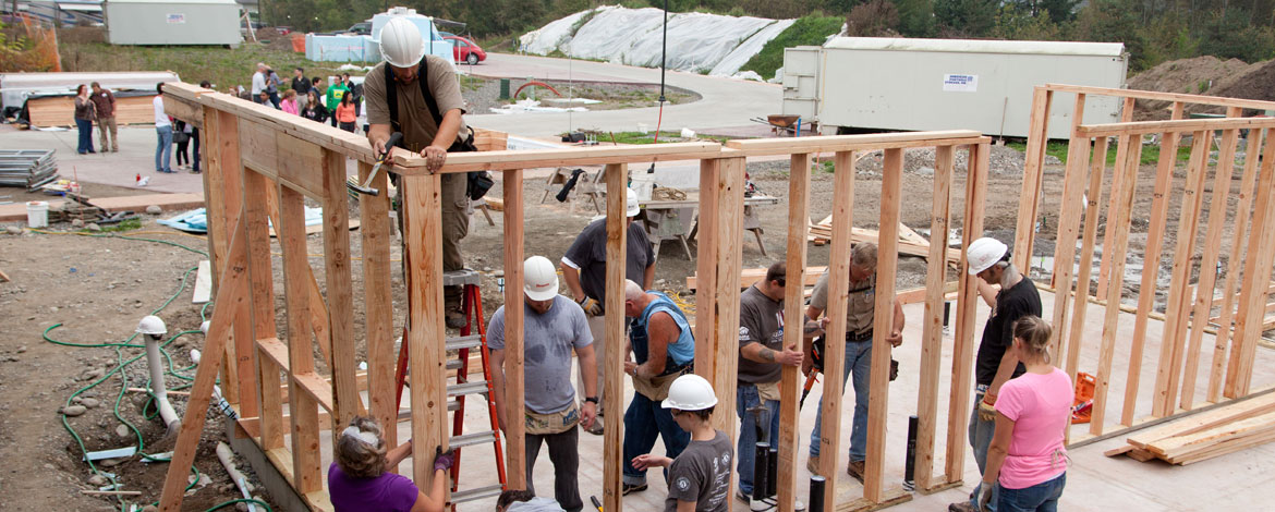 Volunteers, including some from PLU, secure and align a wall at a Habitat for Humanity build site in the Woods at Golden Given, a sustainable 30-home housing community. The house was built for a student who, at the time, was studying marriage and family therapy. (Photo: John Froschauer/PLU)