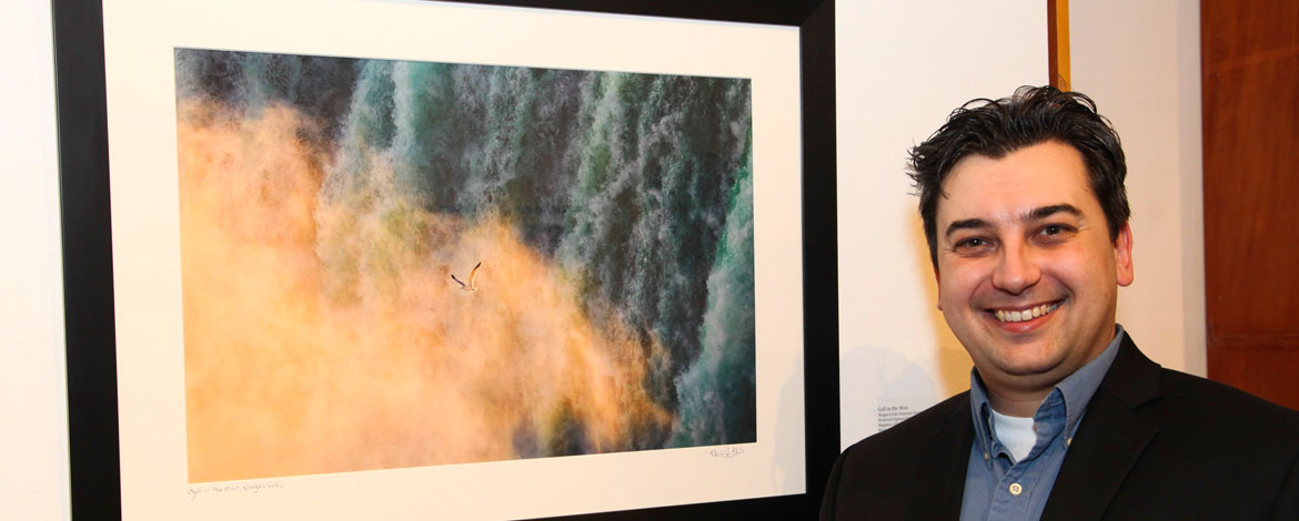 Kevin Ebi '95 stands next to one of his photographs displayed in a gallery. (Photo courtesy of Kevin Ebi)