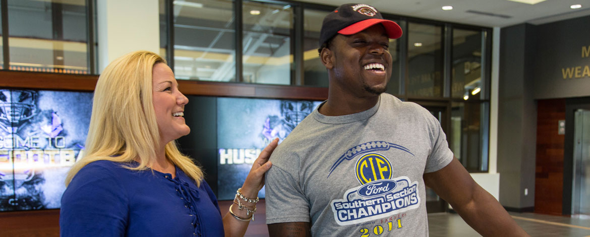 UW running back Lavon Coleman and UW Athletic Director Jen Cohen '94 share laughs at Husky Stadium on Monday, July 18. (Photo by John Froschauer/PLU)