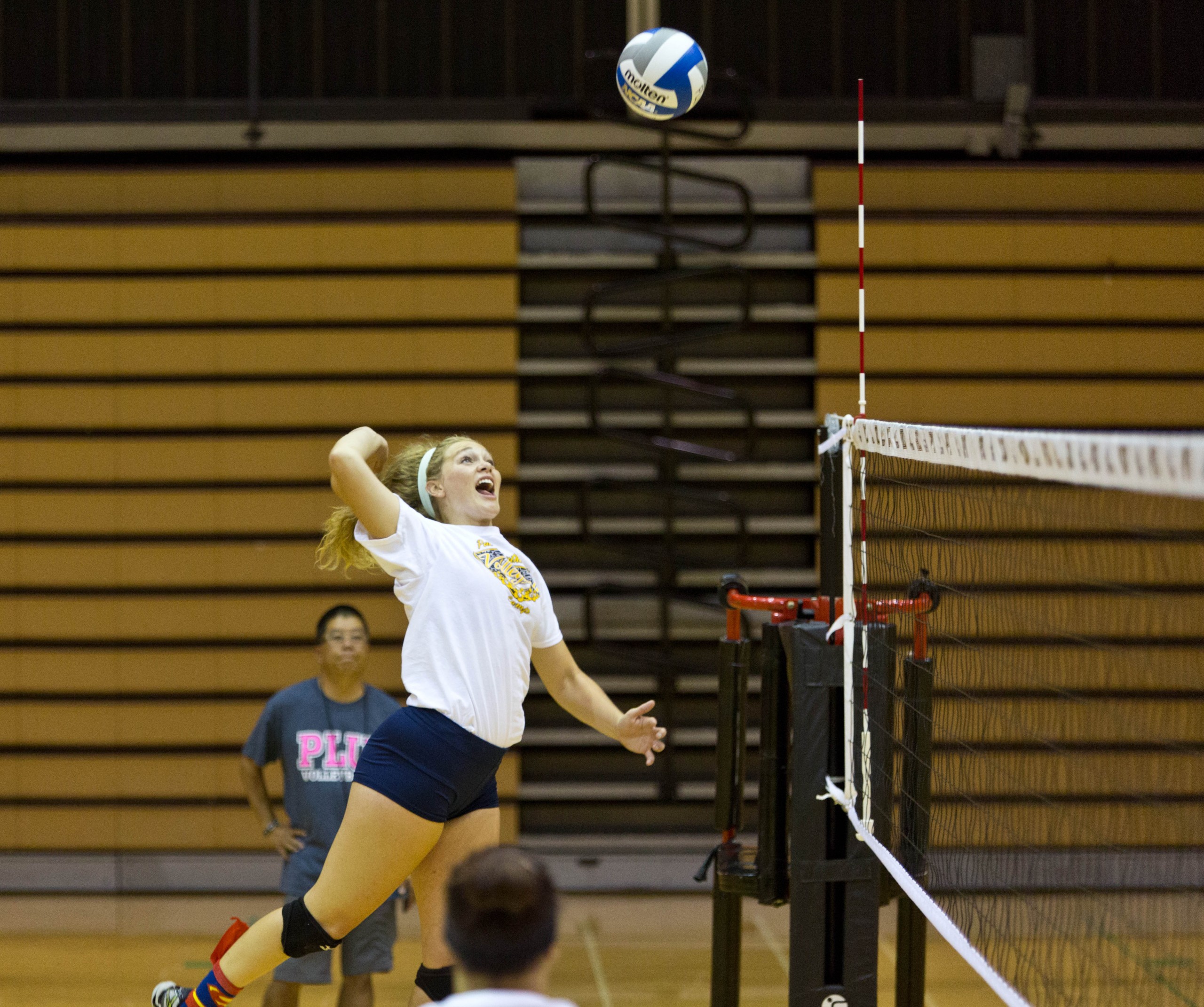 A PLU volleyball player hits the ball over the net