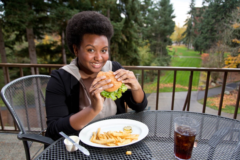 student-food -118-11-9-15 Brooke Thames poses with a cheeseburger while sitting on the balcony of the Anderson University Center.