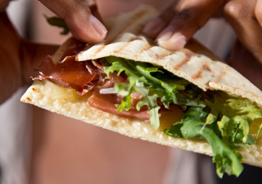 Close up of prosciutto, pecorino tuscano and arugula piadini.