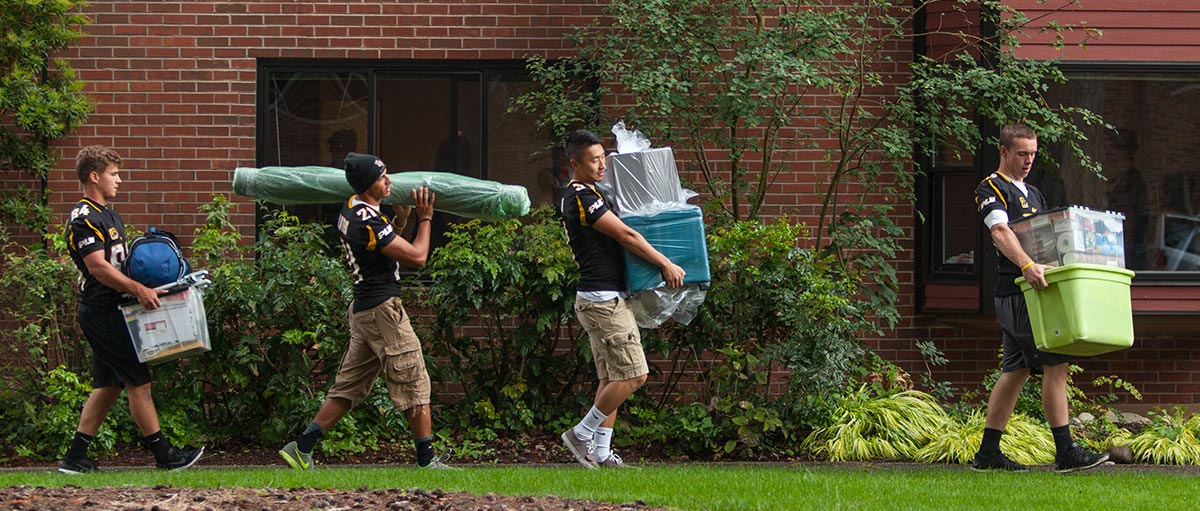 Members of the PLU football team help carry bags on move-in day 2016 at PLU.
