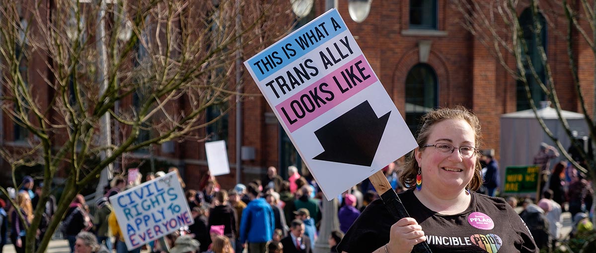 PLU alumna Laura Brewer holding a sign that reads 'this is what a trans ally looks like'