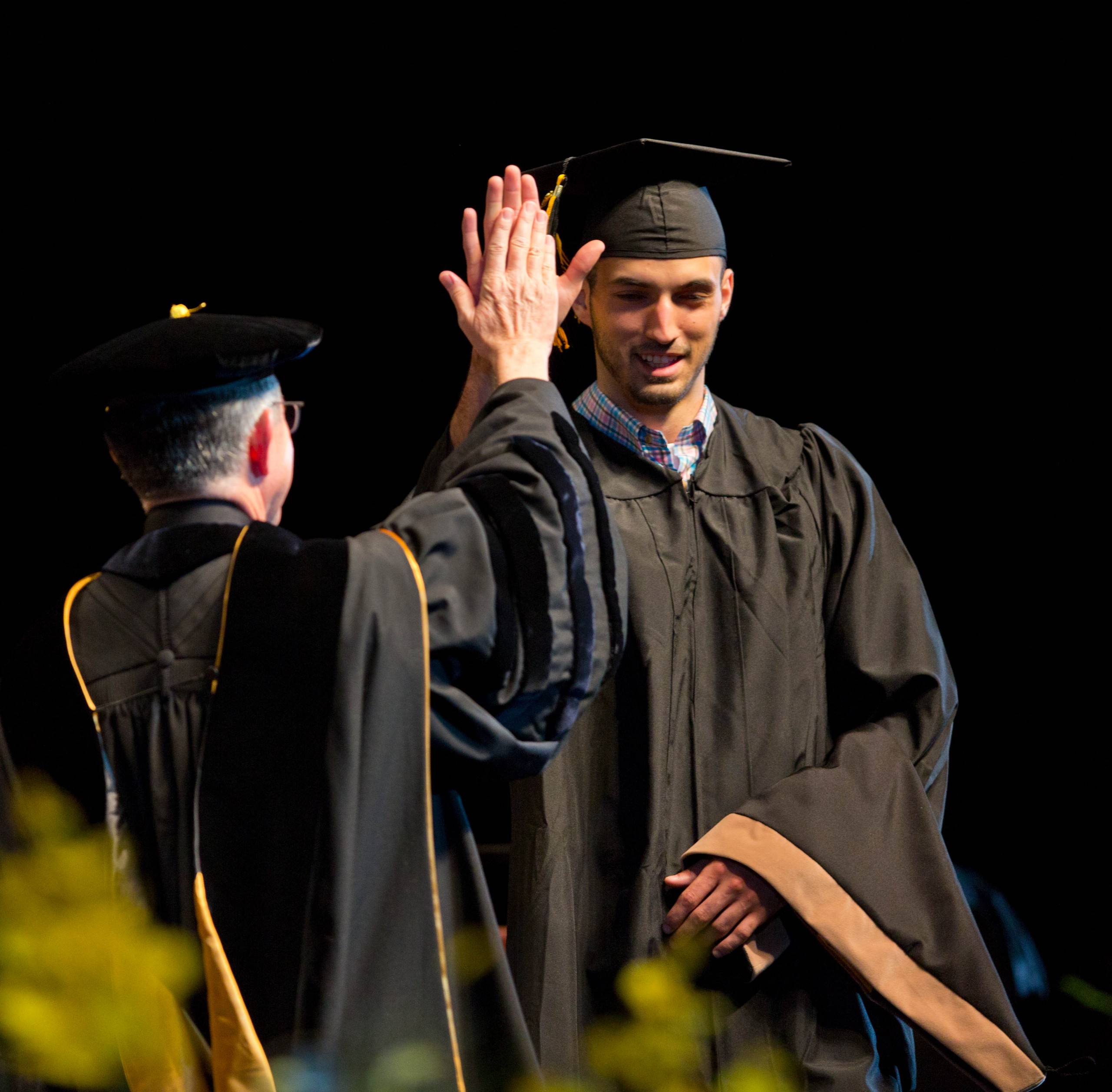 graduate high fives president at commencement